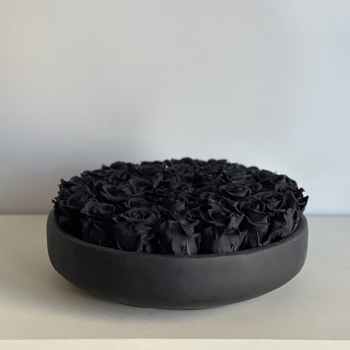 Side view of the Black Rose Serene arrangement, showcasing the soft, velvety texture of the black roses set in a sleek, black ceramic bowl, ideal for creating a bold, contemporary atmosphere.