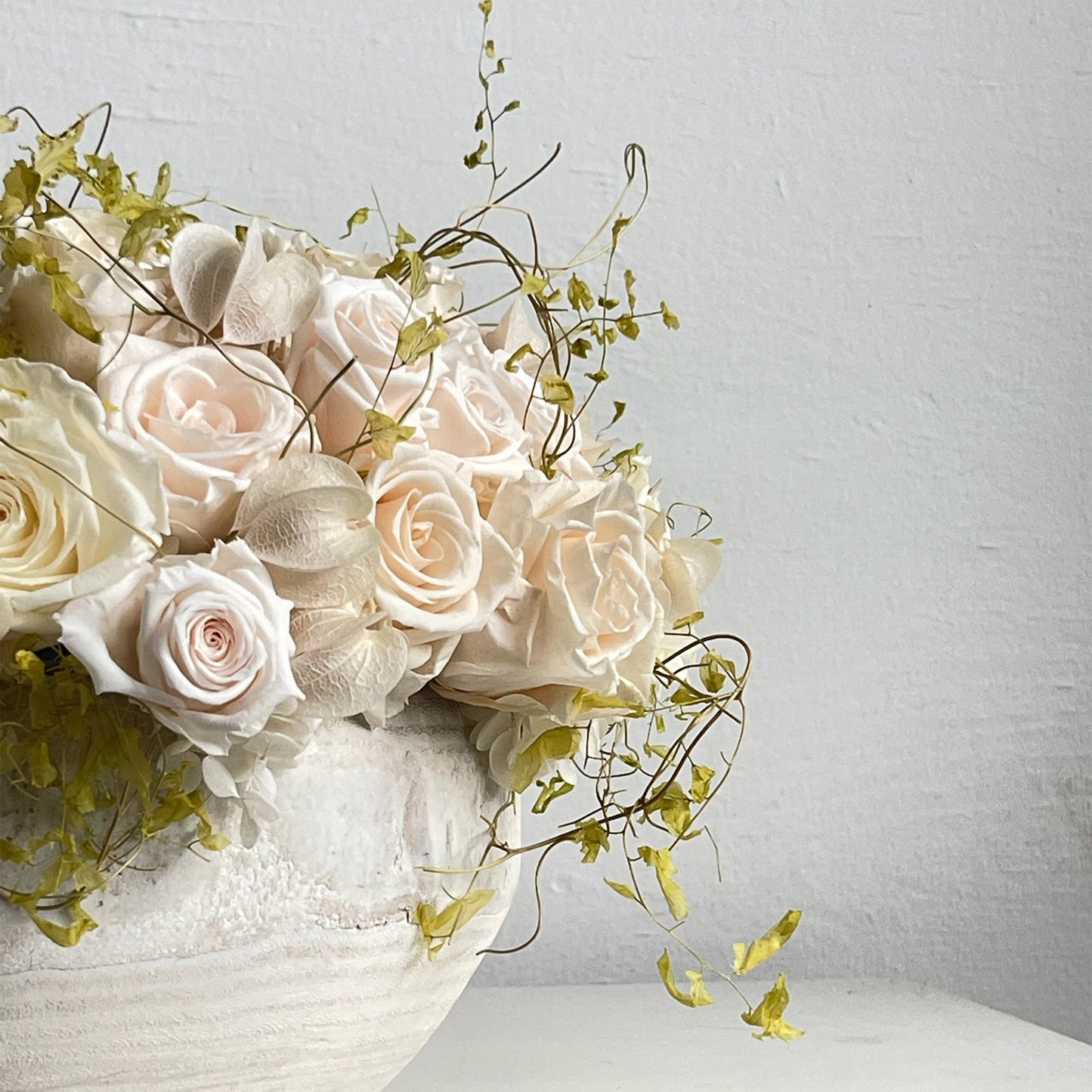 Side view of Delicate Dawn showing preserved roses, smilax, and Japanese-lantern pods.
