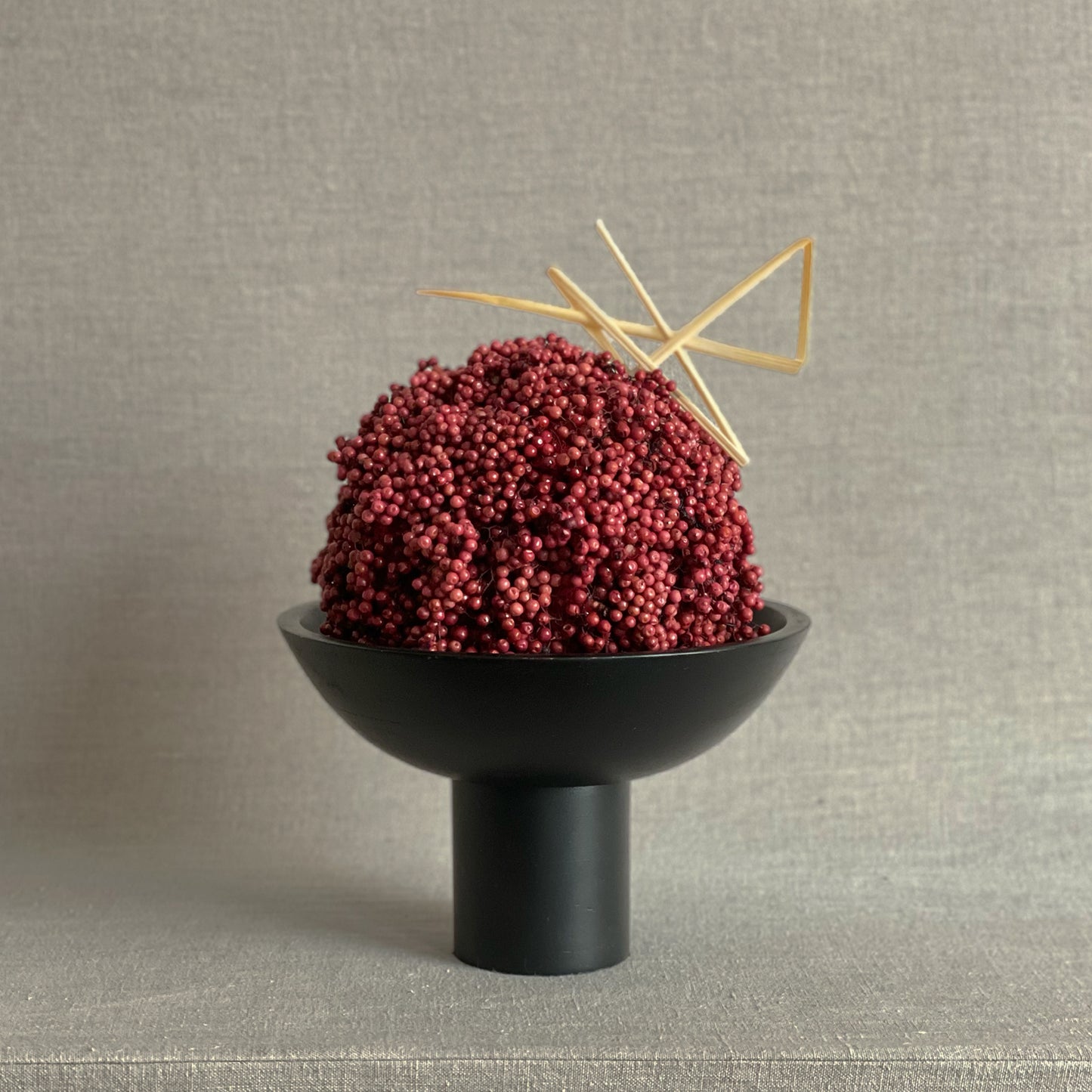 Kokoro Sphere arrangement featuring red preserved California pepperberry in a black pedestal vessel