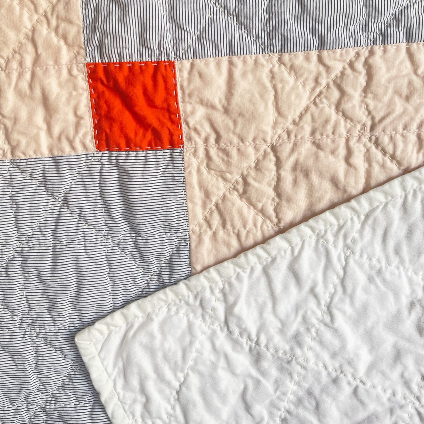 Back of ‘Baby Chan’ quilt by Los Angeles Floral Company, with a clean white backing and Sashiko-style machine quilting.