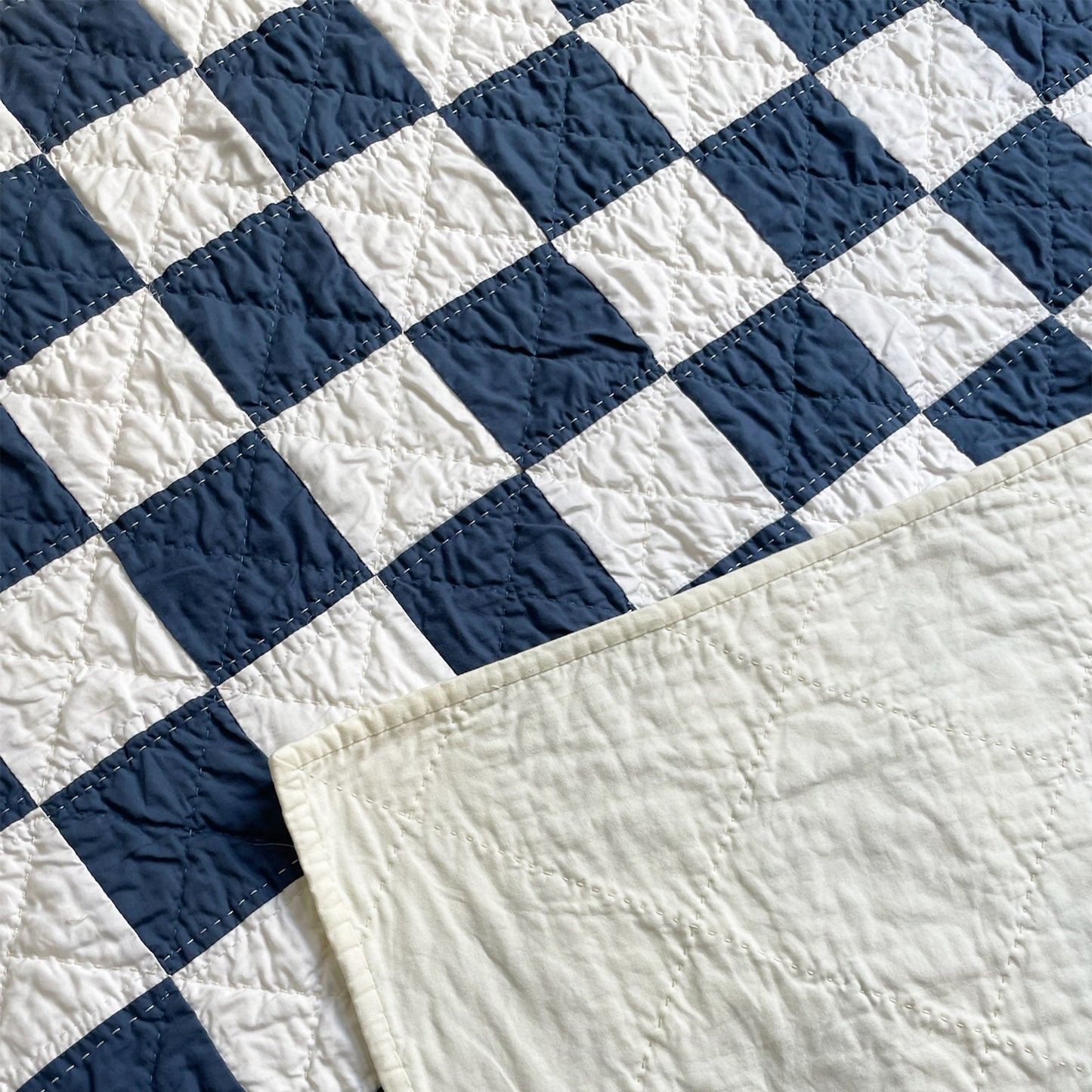 Back of the Hasso Garden quilt, with solid backing and detailed hand-stitching.