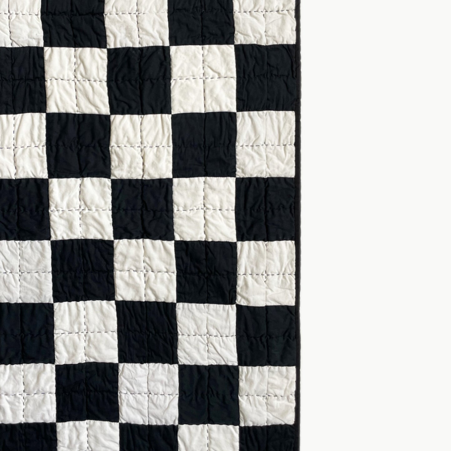 Close-up of the checkerboard pattern in the ‘Hollywood Baby’ quilt by Los Angeles Floral Company, showcasing intricate hand-stitching.