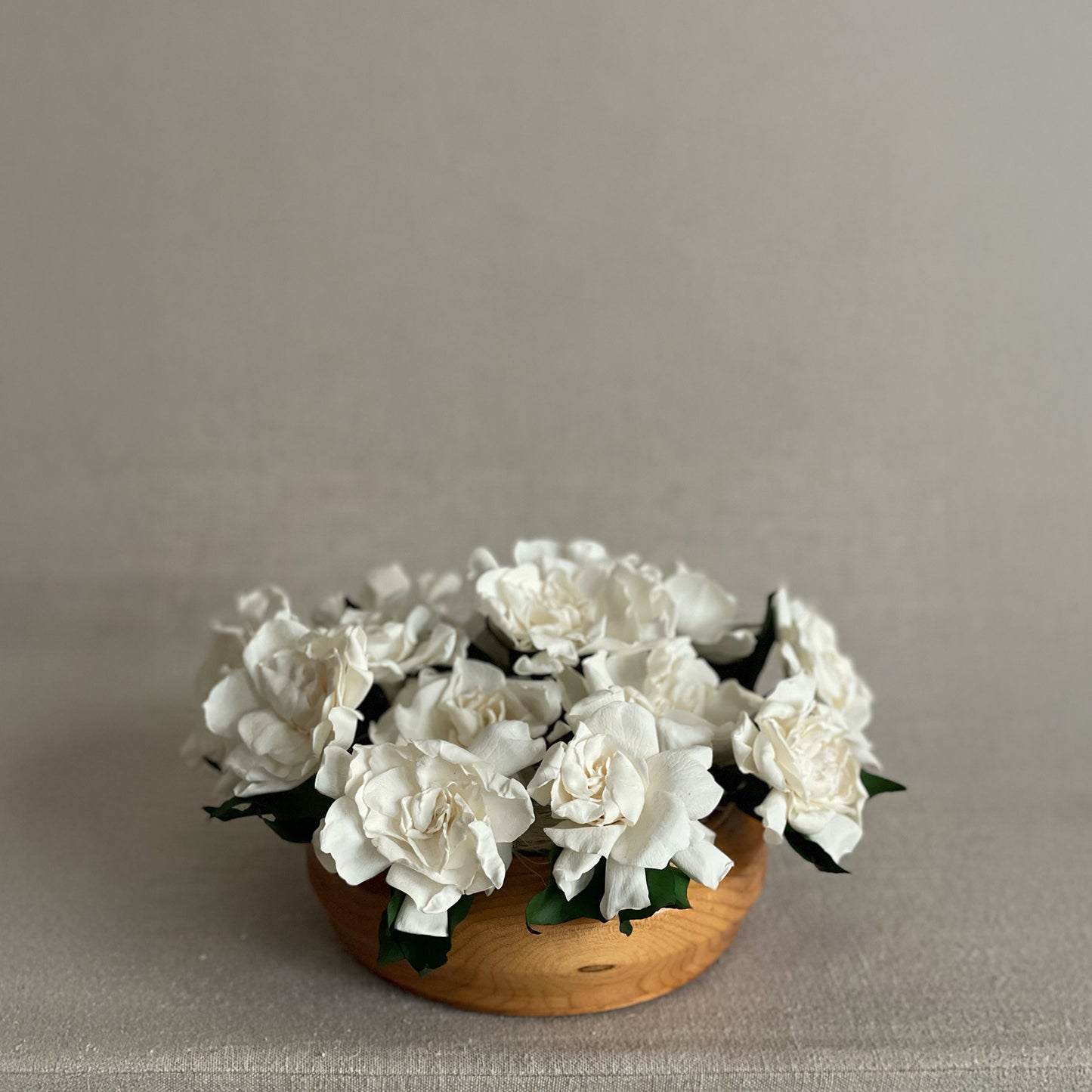 Elegant preserved ivory roses arranged in a sleek teak wood bowl for a modern floral centerpiece