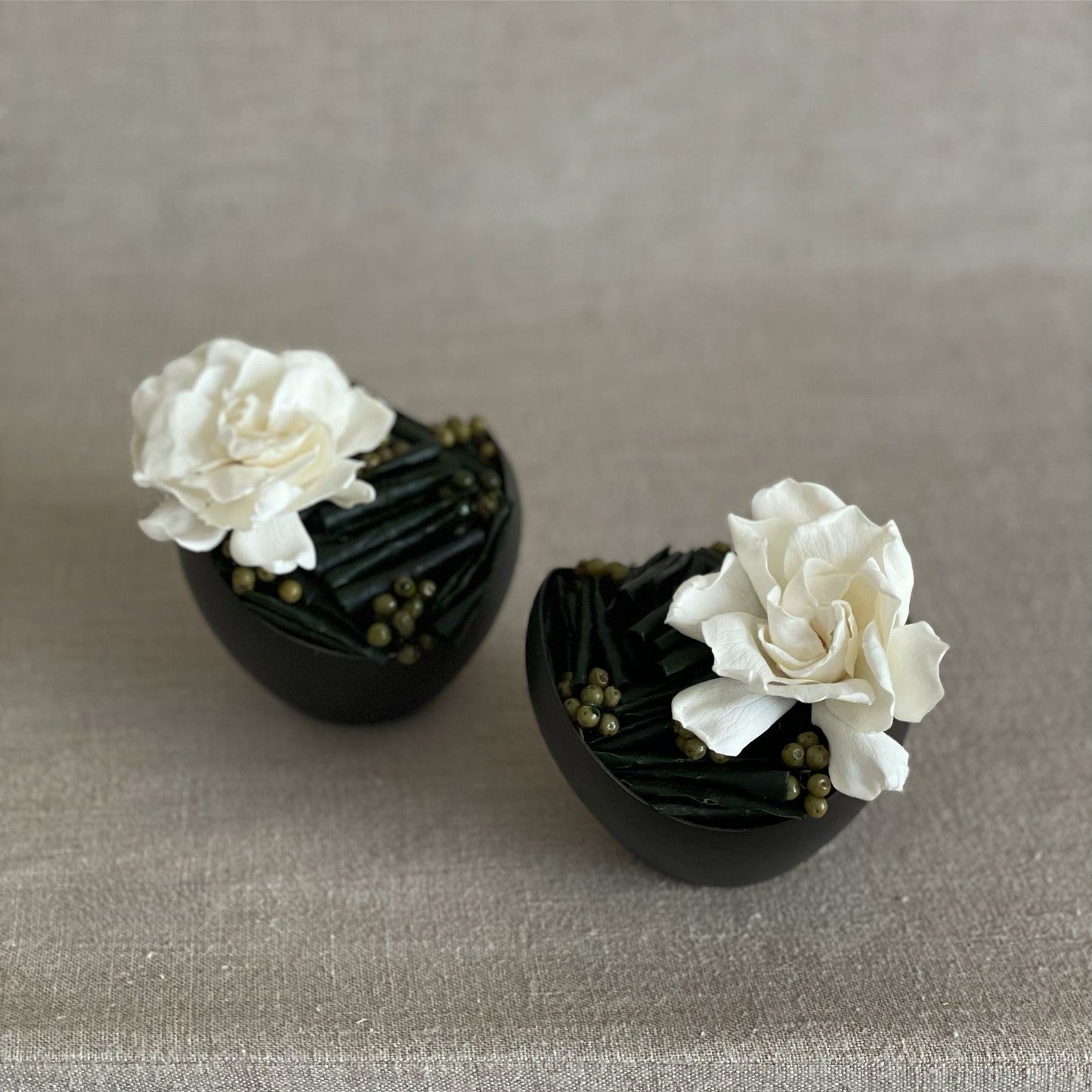 Elegant preserved gardenia with green California pepperberry, displayed in a black minimalist vase, perfect for a bedside or bookshelf accent.