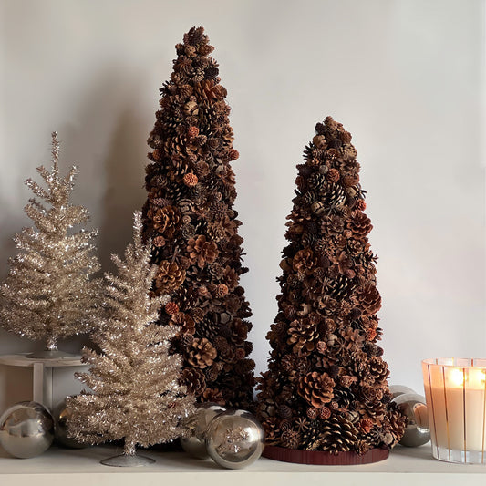 Two preserved pinecone trees styled together with other holiday decor, showcasing the Amberwood Grove in a festive setting.