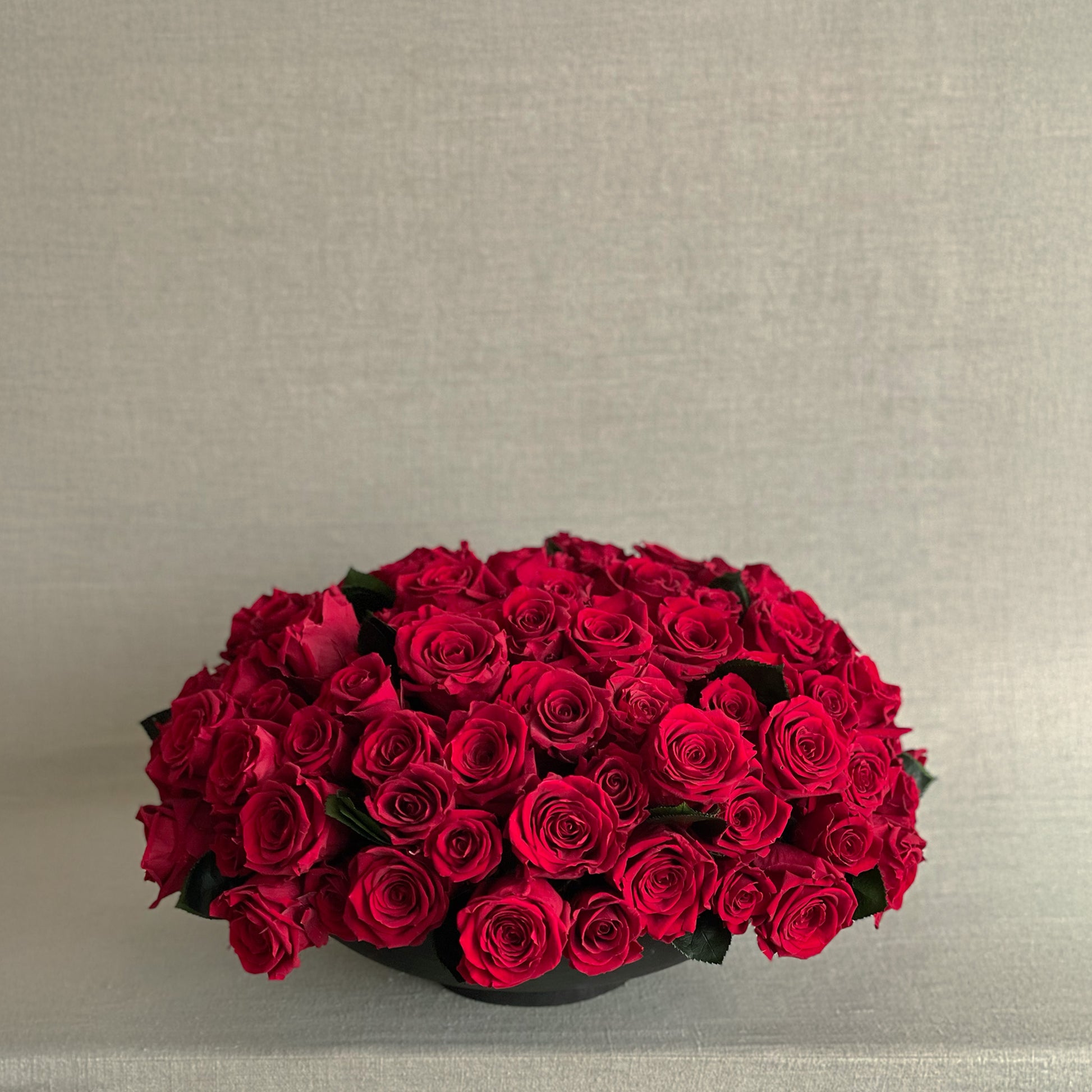 Luxurious red preserved roses elegantly arranged in a sleek black bowl for Valentine’s Day.