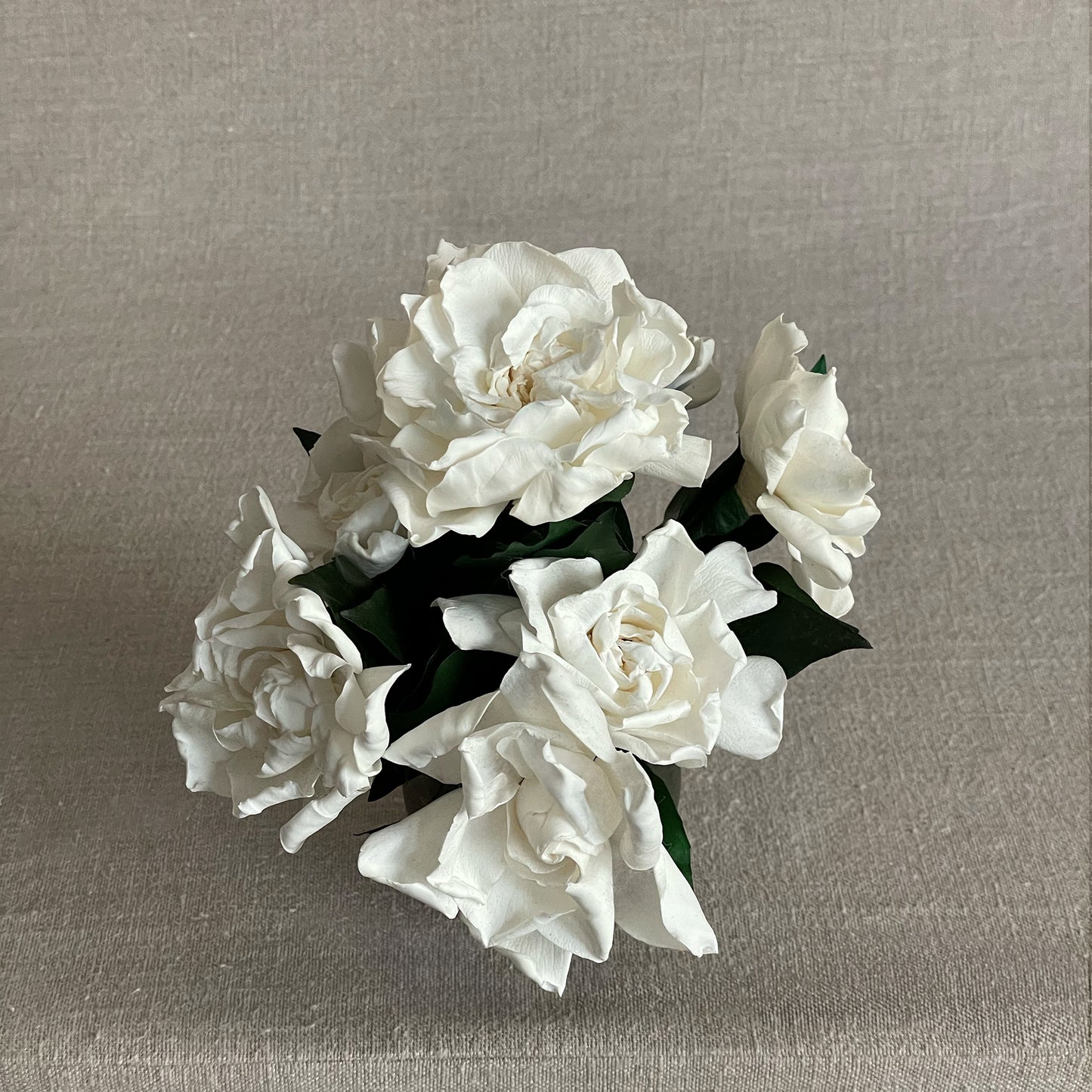 Preserved white gardenias elegantly arranged in a hand-crafted bronze vase