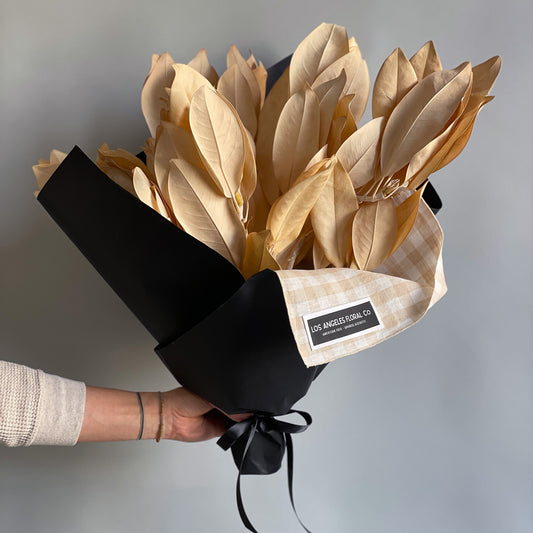 A bundle of preserved bleached magnolia branches, elegantly wrapped in a furoshiki-inspired cloth, showcasing the soft, natural hues of the golden magnolia.