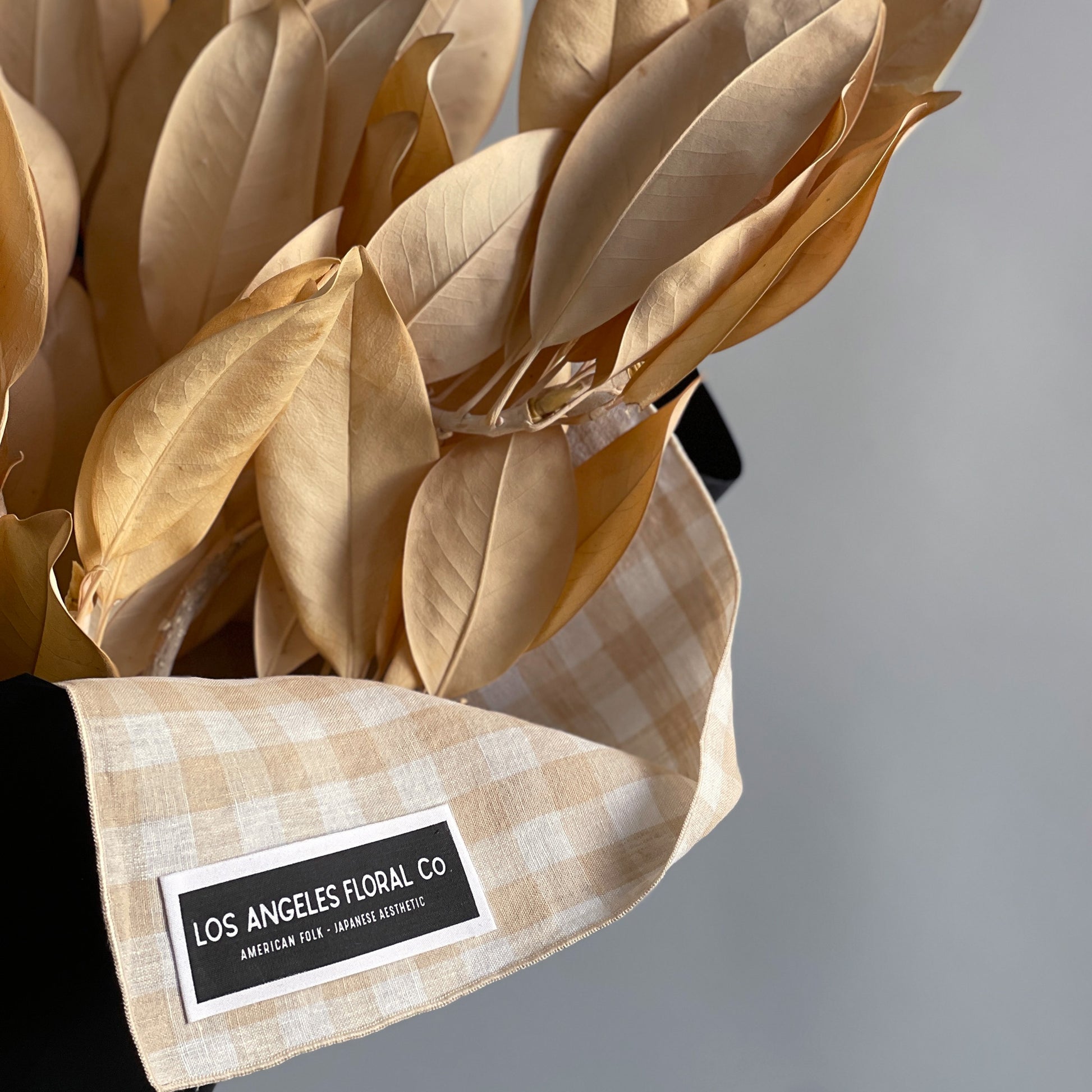 Another close-up view of preserved golden magnolia branches, artfully bundled and wrapped in a furoshiki cloth, highlighting the delicate texture and elegant presentation.