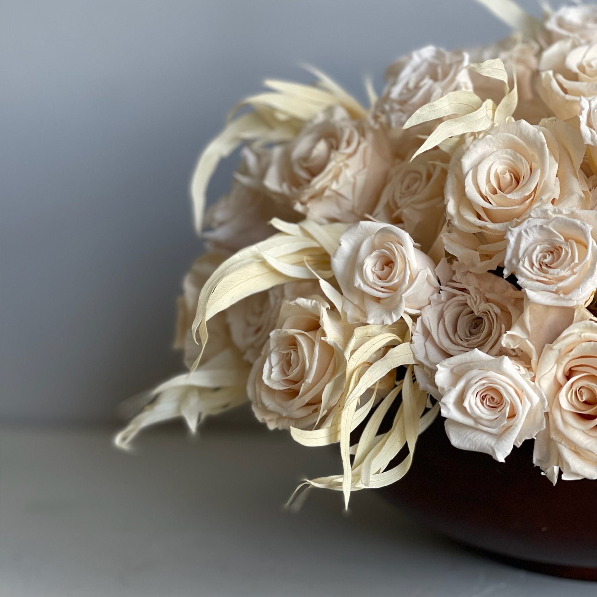 Side view of the Ivory Rosewood Bowl, highlighting the delicate arrangement of preserved ivory roses paired with willow eucalyptus, set in a rich, earthy wooden bowl.