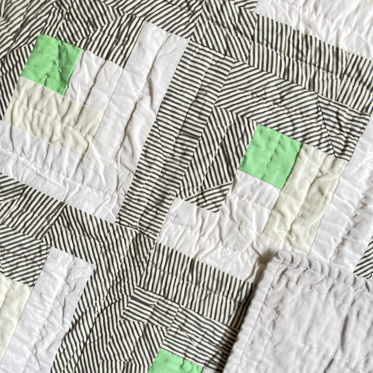 Close-up of the ‘1925’ quilt with Art Deco influences, highlighting detailed hand-quilting and striped fabric patterns by Los Angeles Floral Company.