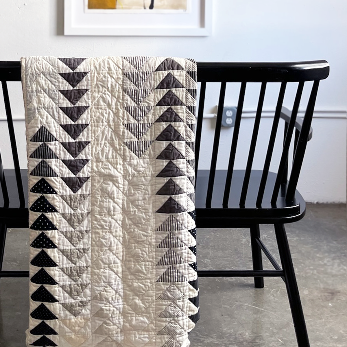 Hand-quilted chevron pattern quilt draped over a black bench, featured on the American Folk page within Los Angeles Floral Company’s Inspirations section.