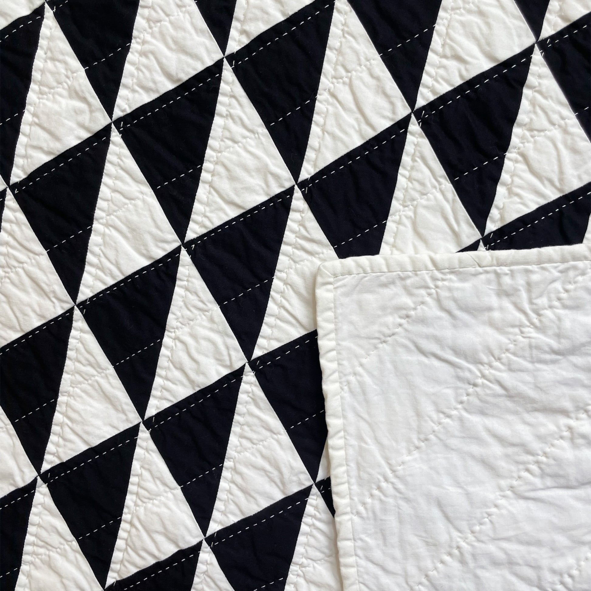 Back of ‘b/w-hst’ quilt by Los Angeles Floral Company, with solid white backing and detailed hand-stitching.