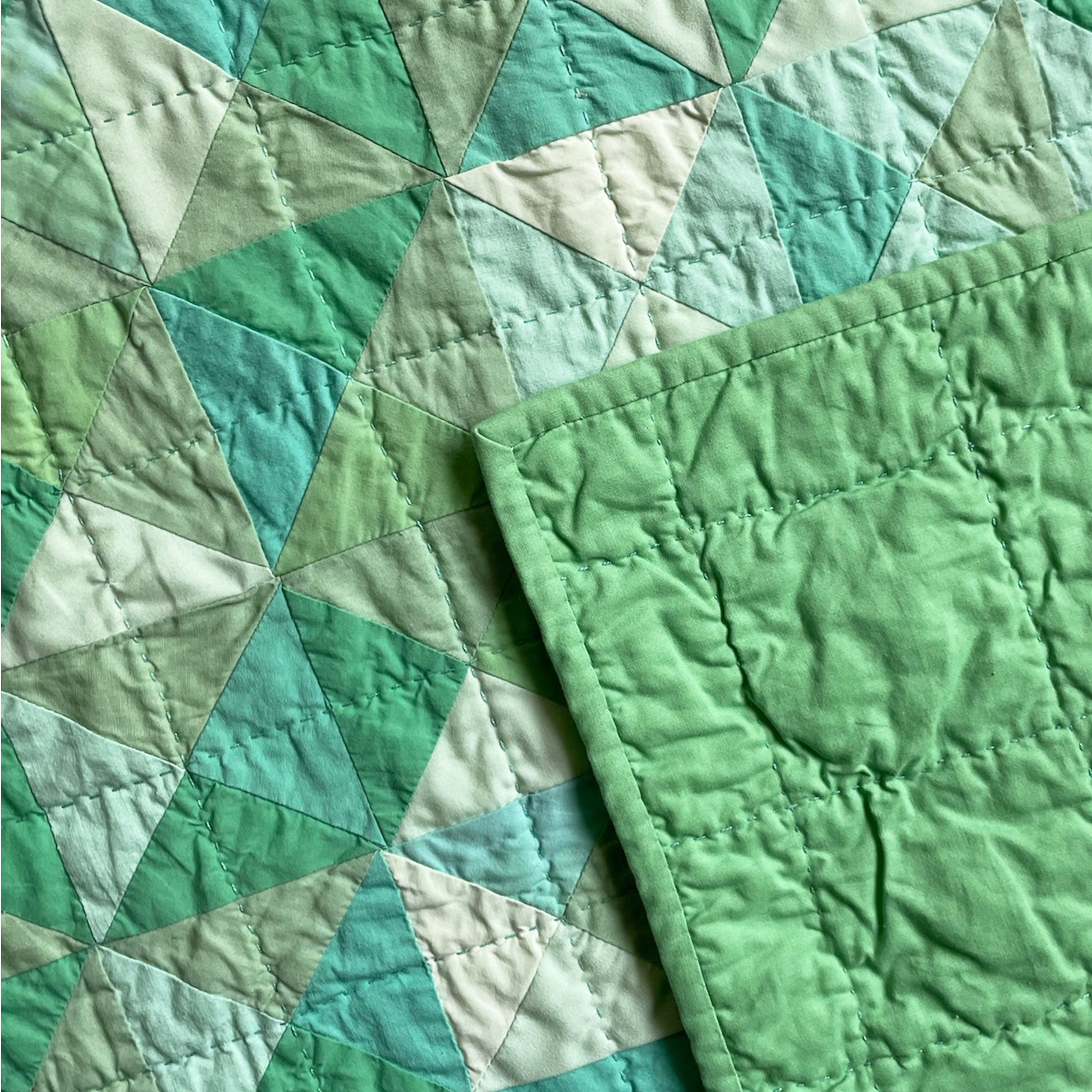 Back of ‘Hisui [Jade]’ quilt by Los Angeles Floral Company, with solid green backing and detailed hand-stitching.