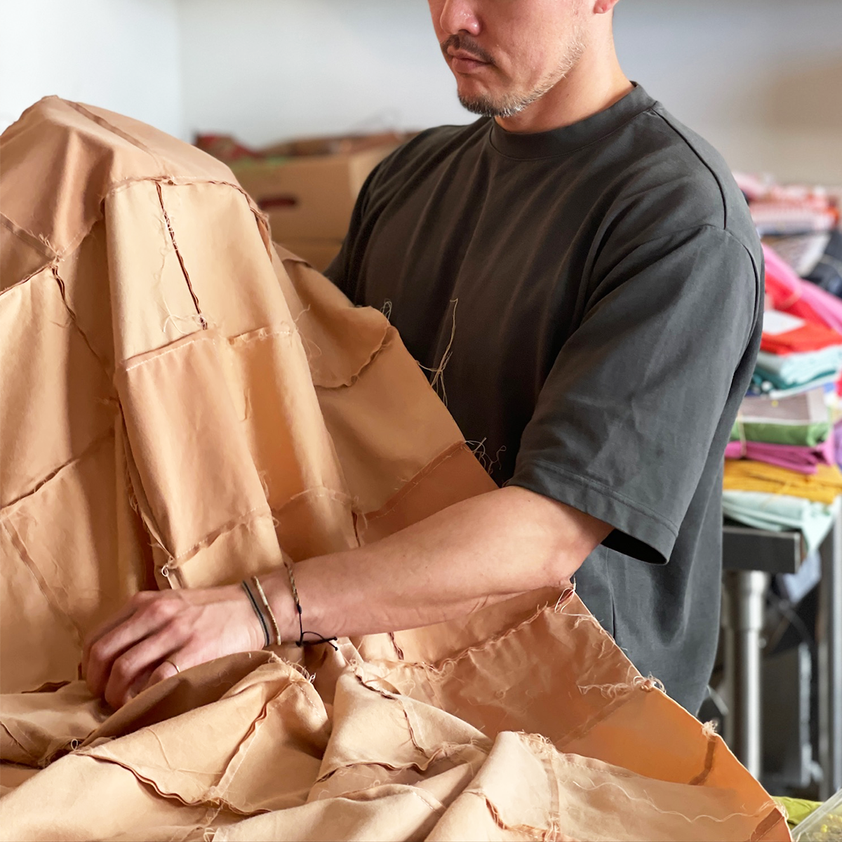 Keigo, co-founder of Los Angeles Floral Company, handcrafting a quilt with reclaimed, sustainable nude/taupe fabric in their DTLA studio, showcasing the brand’s dedication to artisanal craftsmanship and sustainability.