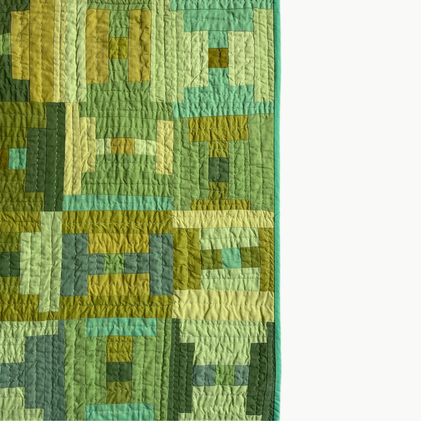 Close-up of the Courthouse Steps pattern in the ‘Moss Steps’ quilt by Los Angeles Floral Company, showcasing various green reclaimed fabrics and Sashiko-style hand-stitching.