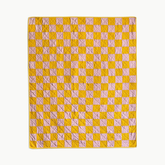 Hand-stitched ‘Oh, Baloney!’ quilt by Los Angeles Floral Company in golden yellow and pink checkerboard pattern, designed with playful hues.