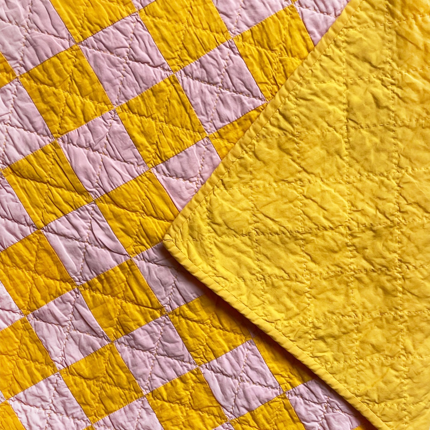 Back of ‘Oh, Baloney!’ quilt by Los Angeles Floral Company showing solid golden yellow fabric and stitching details.