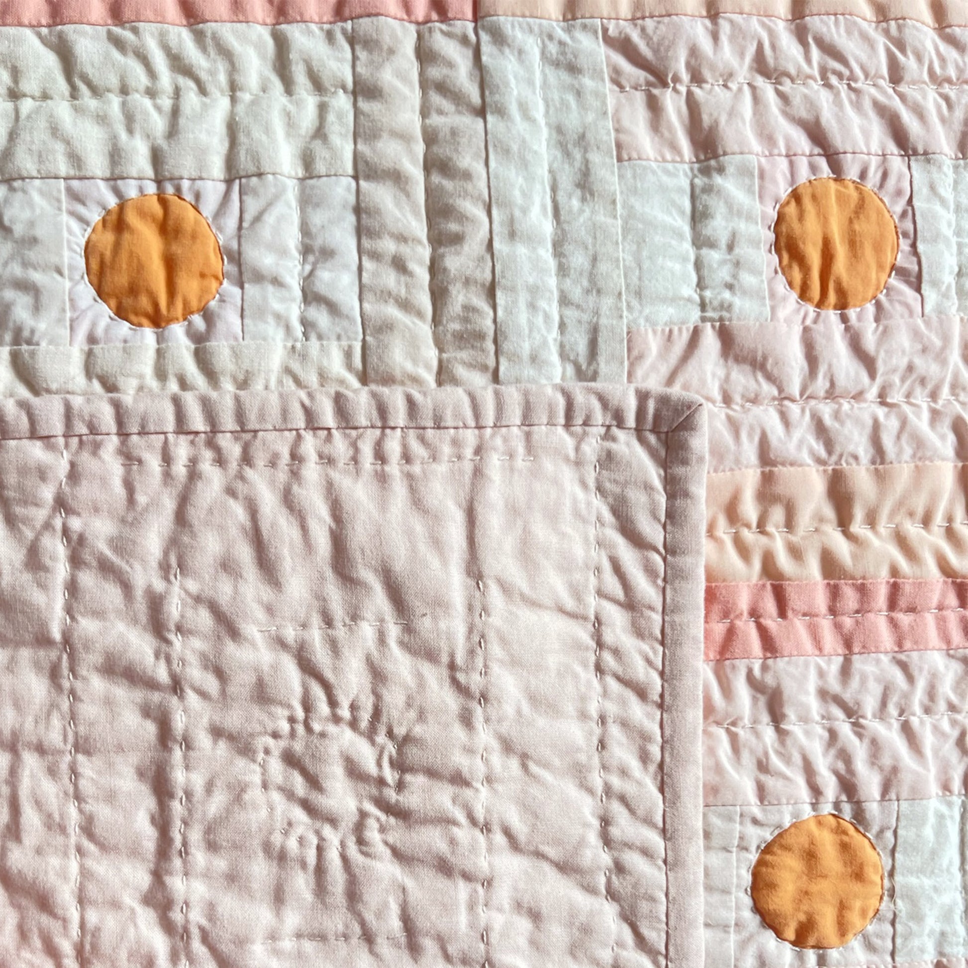 Back of the Pickled Plum quilt by Los Angeles Floral Company showing soft stitching and orange circle detail.