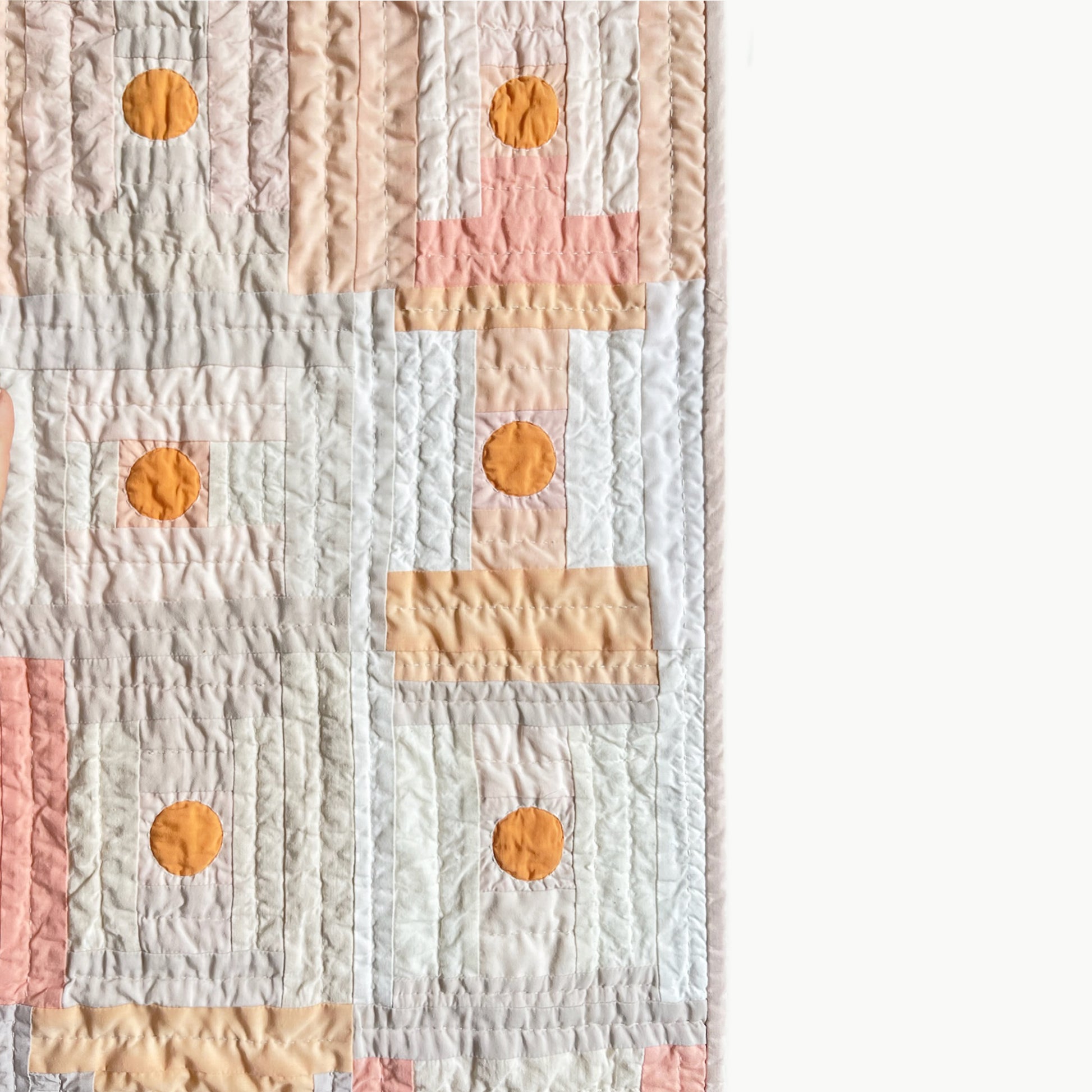 Close-up of the peach, plum, and beige quilt block by Los Angeles Floral Company with orange circle, showcasing Sashiko-style hand-stitching.