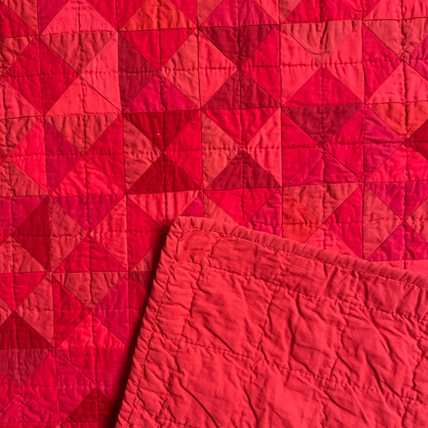 Back of R.A.E.’s quilt, with solid red backing and detailed hand-stitching.