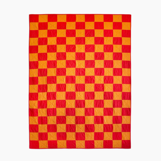 Hand-stitched ‘Tokyo Sunset’ throw-size quilt by Los Angeles Floral Company, featuring bold red and orange checkerboard pattern inspired by a Tokyo sunset.