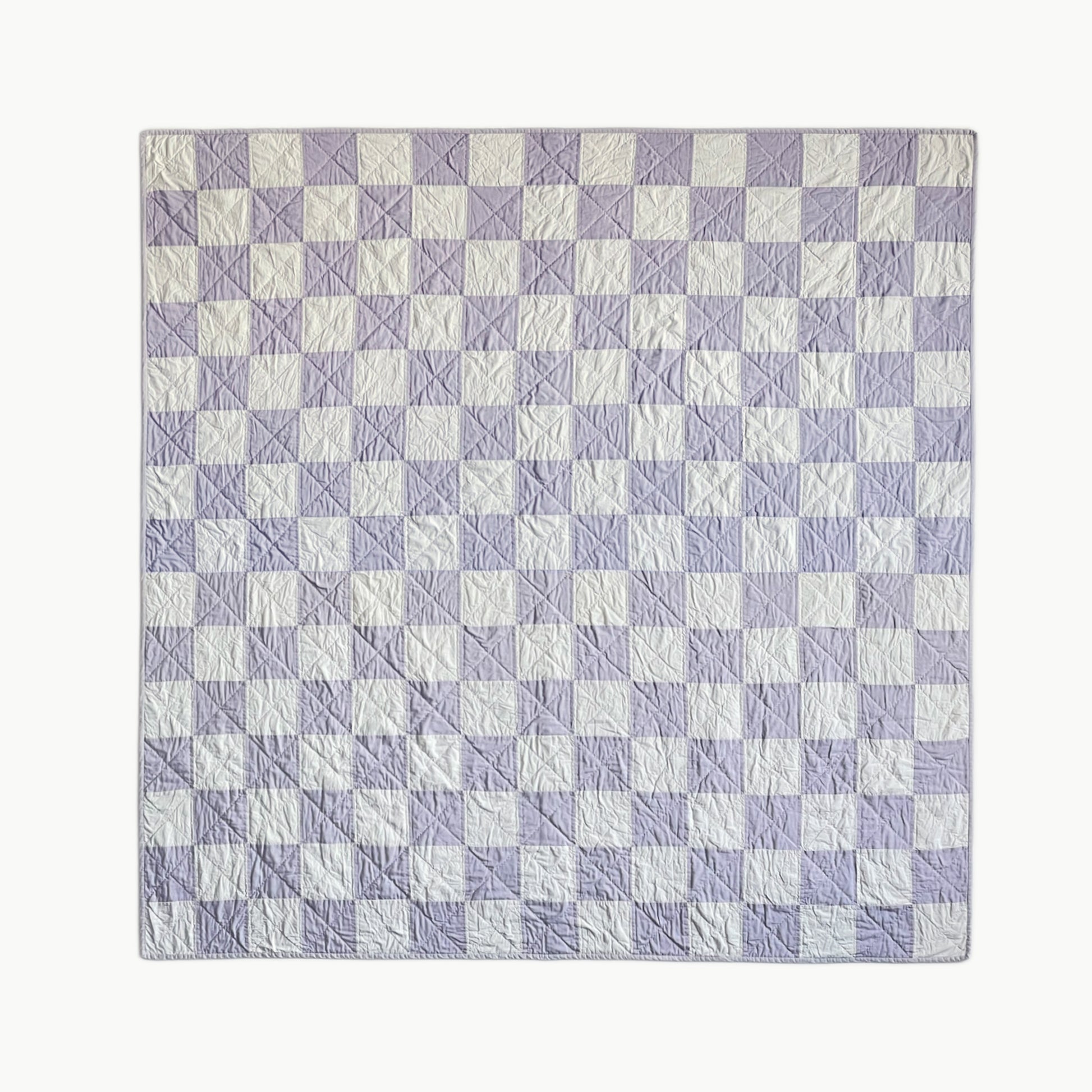 Hand-stitched 'Waft & Wisp' throw-size quilt by Los Angeles Floral Company, featuring a delicate blue and white checkerboard pattern inspired by smoke rising from smudge sticks.