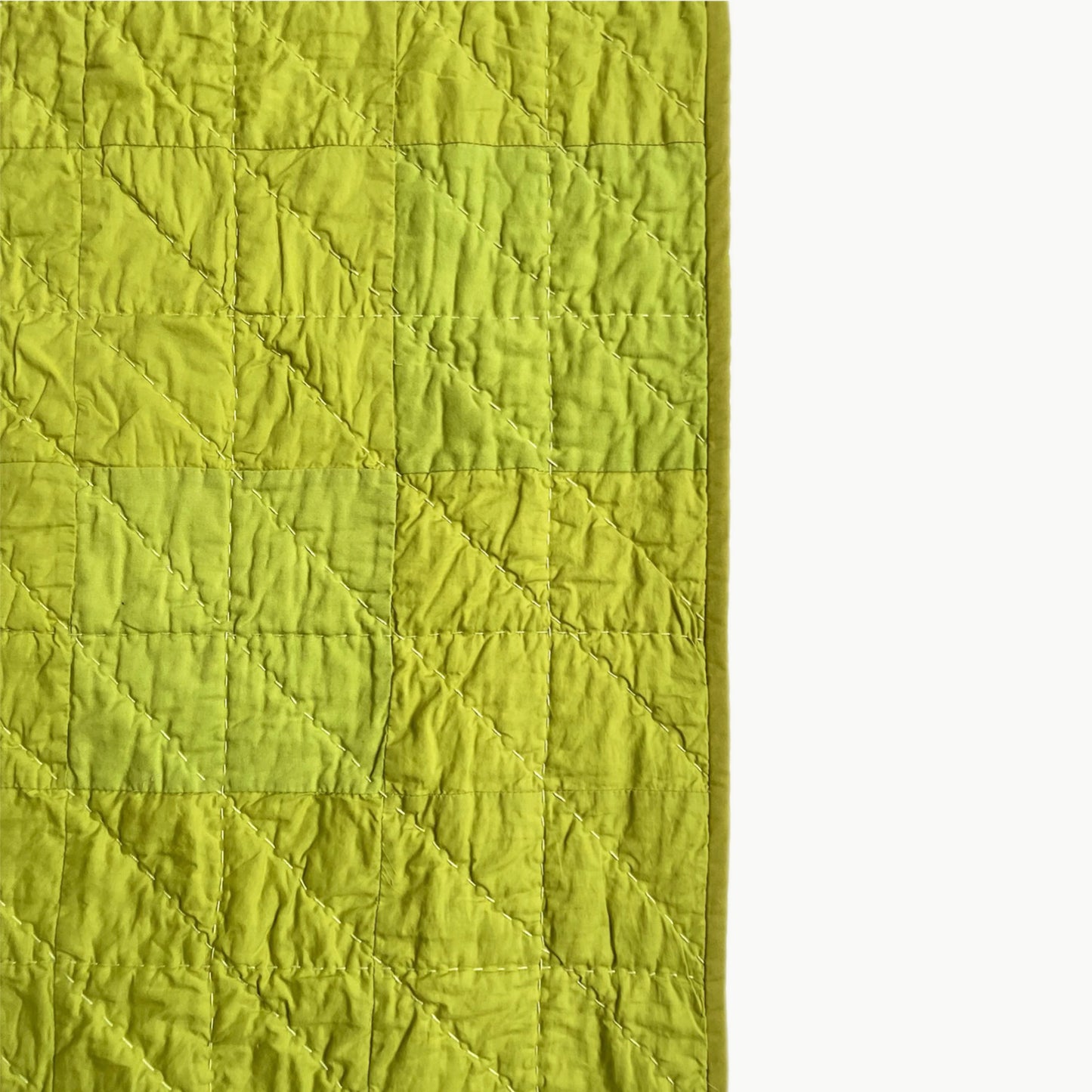 Close-up of the vibrant green patchwork in the Wakakusa quilt, showcasing Sashiko-style hand-stitching.