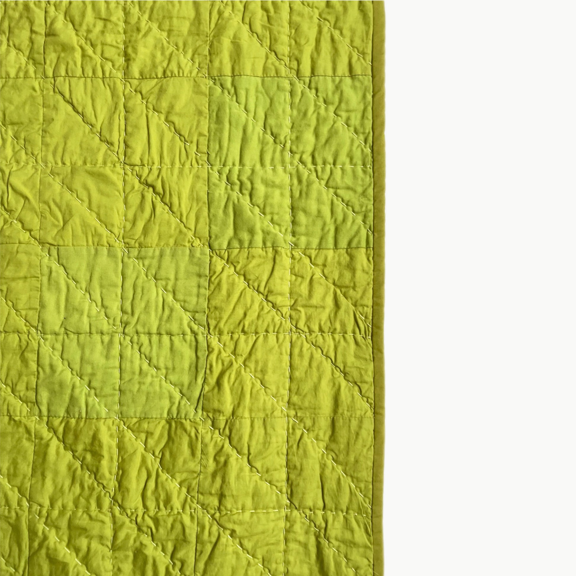Close-up of the vibrant green patchwork in the Wakakusa quilt, showcasing Sashiko-style hand-stitching.