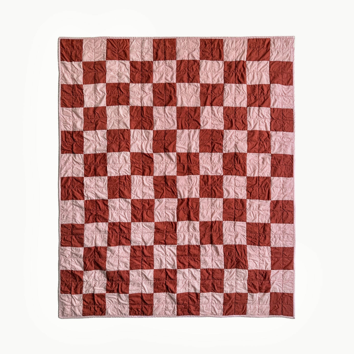 Full view of pink and rust checkerboard hand-quilted throw quilt inspired by Nat Love, Showman Series Act One.