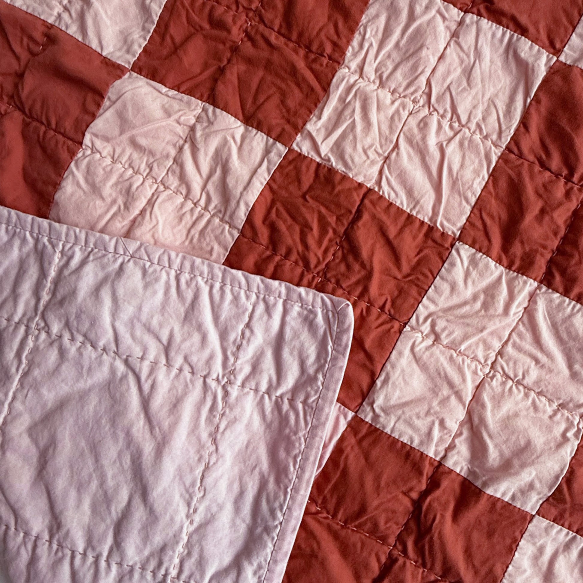 Close-up of hand quilting stitches and pink backing on Nat Love heirloom throw quilt.
