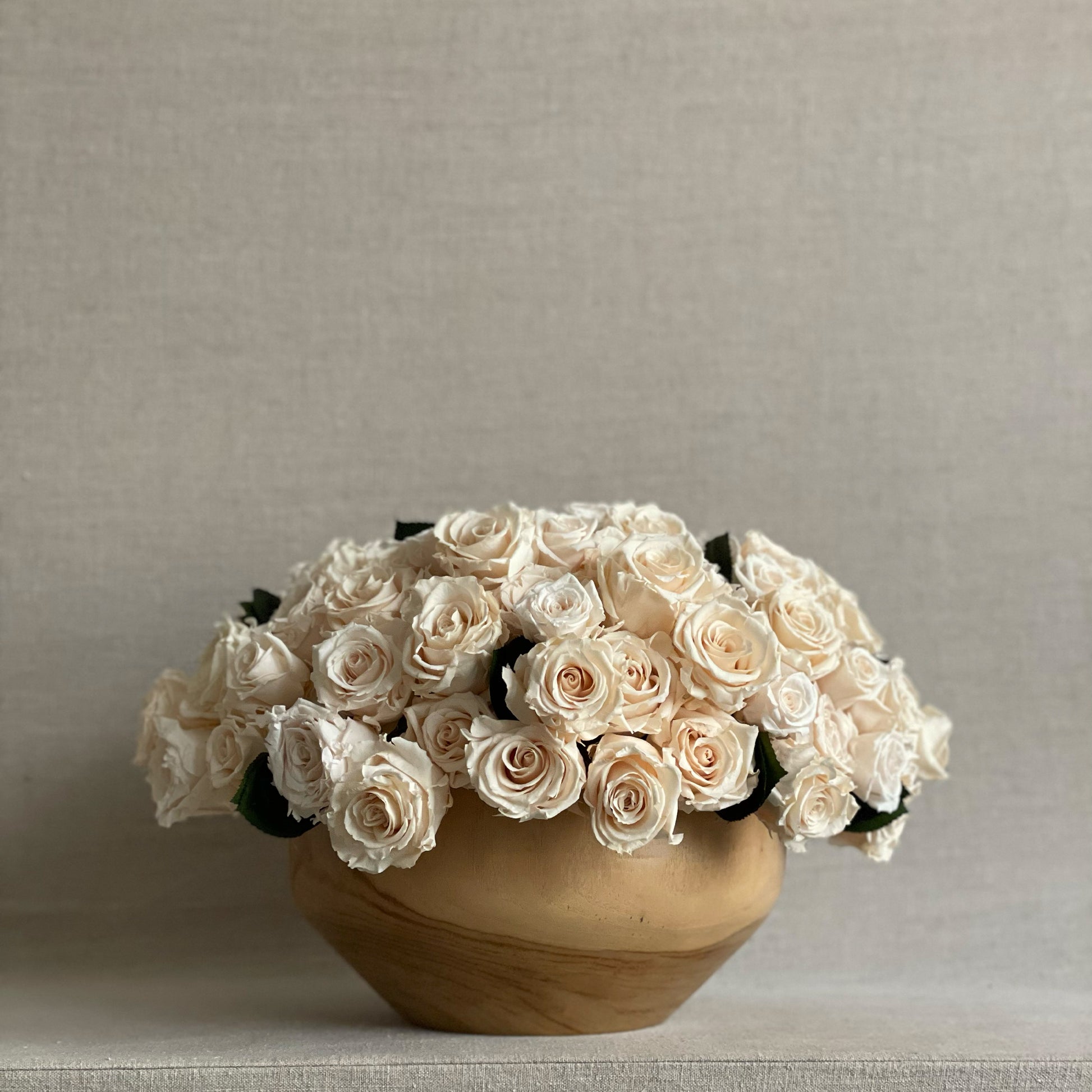 Teakwood Ivory Rose Bowl featuring 150 preserved ivory roses in a contoured teak wood bowl.