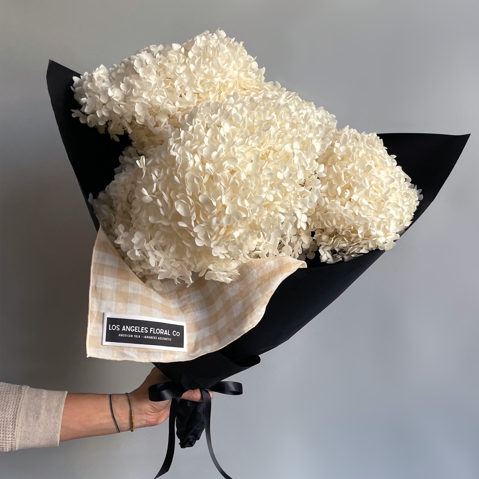 A bundle of preserved white hydrangea blooms wrapped in furoshiki-inspired cloth, showcasing their soft texture.