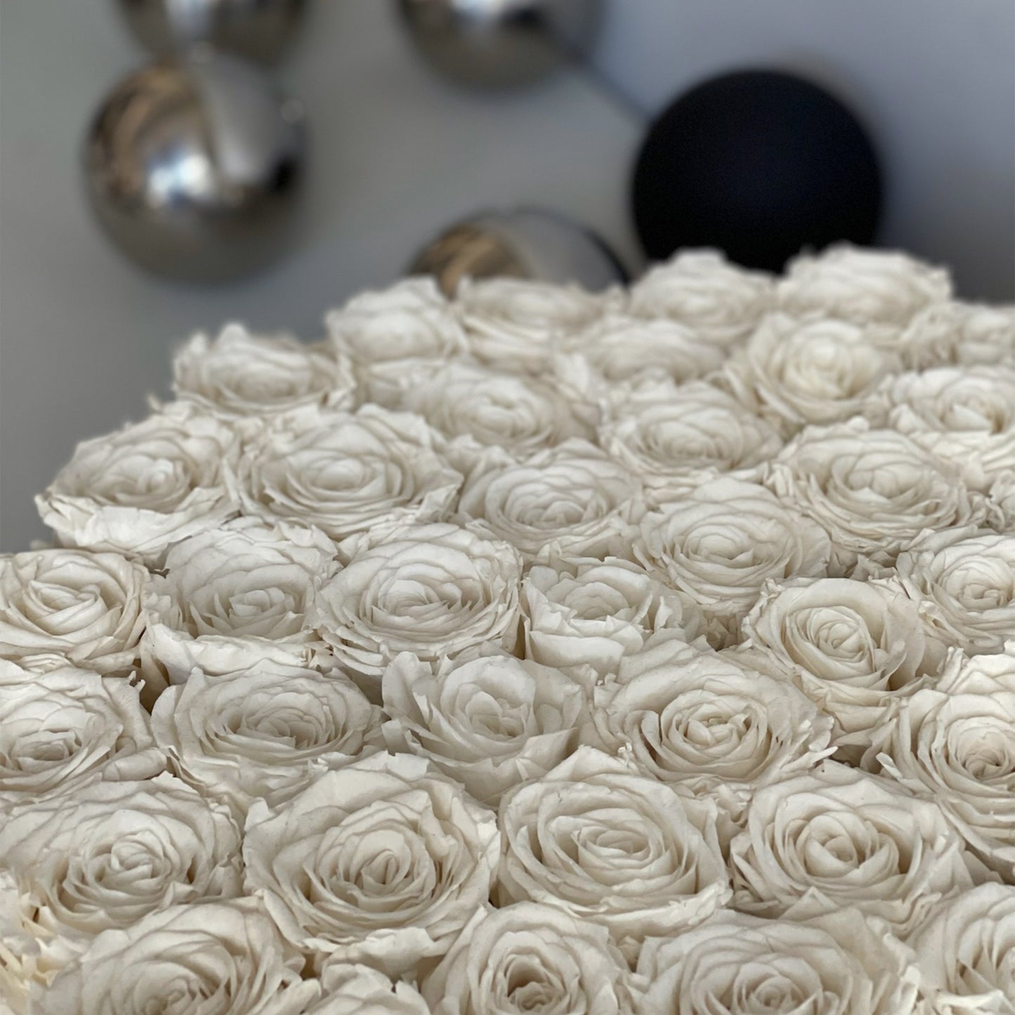 A detailed close-up of preserved white roses in the serene bowl, highlighting the elegance and soft petals against a clean backdrop.